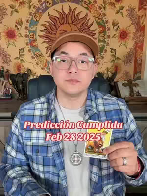 A man in glasses and a baseball cap holds a tarot card, with text overlaying the image, and a tapestry-style background.