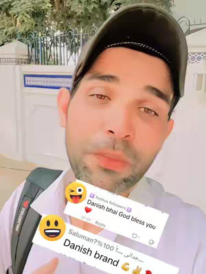 A selfie-style shot featuring a light-skinned man with dark hair, wearing a dark cap and white shirt. He's looking at the camera, and there are two comment bubbles overlaid on the image. The background suggests an outdoor setting, possibly a building with a white facade.