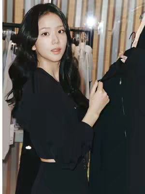 The cover image features a person with black hair, dressed in a black top and bottoms, holding a clothing item. The background is a clothes rack and neutral-colored wall.