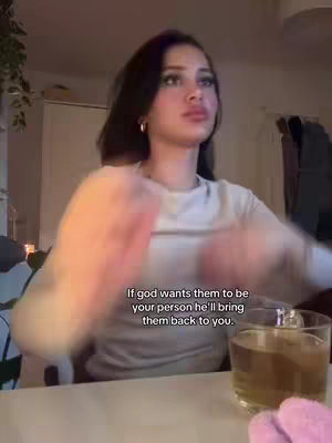 The image shows a woman looking up slightly, her hands are raised up and blurred as if gesturing or moving. She has dark hair and is wearing a light colored long-sleeved shirt. In the foreground, is a glass of liquid, probably tea . Text overlayed features a romantic message. The background appears to be an indoor setting, perhaps a living room.