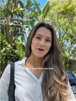 A woman with long, highlighted brown hair stands in front of lush green foliage and a blue sky. She wears a white blouse and has a black bag strap over her shoulder. Text overlayed reads, 'I heard a quote that once said'. A dark car is visible in the background.