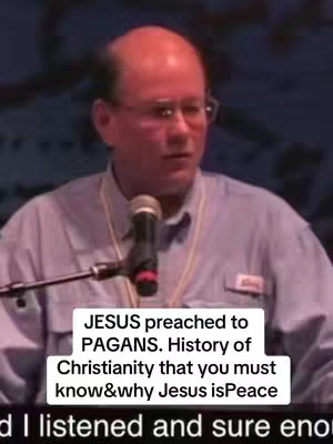 A man with glasses speaking in front of a microphone with text overlaid on the bottom.