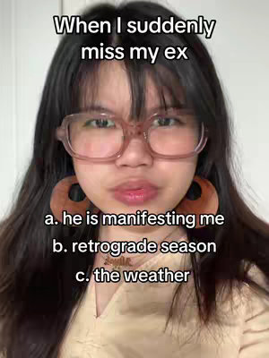 A close-up shot of a light-skinned woman with long, dark hair and glasses looking at the camera. Above her are the words "When I suddenly miss my ex." Three options follow below: "a. he is manifesting me", "b. retrograde season", and "c. the weather." The background is a plain, neutral color.