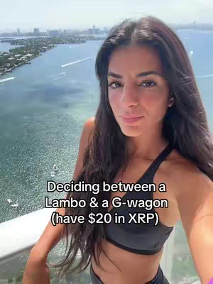 A selfie-style shot with a woman in the foreground against a bright, scenic background of water and a distant cityscape. The woman has long dark hair and is wearing a dark top. Text is overlaid on the image.