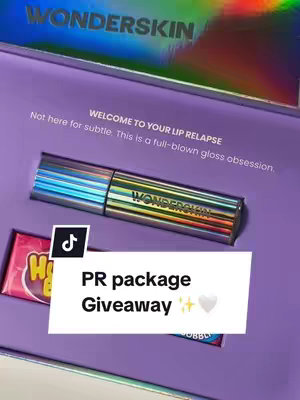 The cover image features a purple box containing a lip gloss tube, a candy wrapper, and a promotional text overlay. The lip gloss tube is iridescent with the brand name WONDERSKIN, placed in the center. The candy wrapper sits to the left with the brand name and logo visible. The overlay text says 'PR package Giveaway' in white letters, and there is a TikTok icon in the background. The composition is well-lit, with focus on the product and the text indicating a giveaway event.