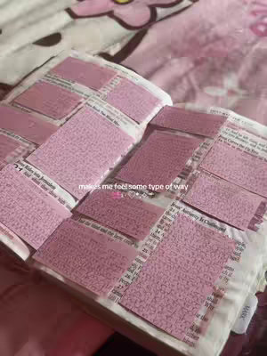A close-up shot of an open book covered in pink sticky notes. The book is lying on a pink floral-patterned cover. The sticky notes are filled with what seems to be handwritten notes. The text overlay says 'makes me feel some type of way'.