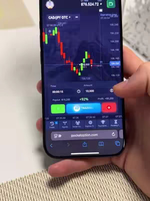Image shows a smartphone screen displaying a trading interface. A hand is interacting with the screen, specifically highlighting a financial chart with price fluctuations, and options for trading actions.  The app's interface is predominant, showing market data  with various control buttons.