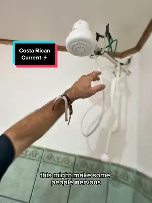 The image shows a person's arm reaching towards a white shower head. The shower head is mounted, and the person's arm is extended as if interacting with it. The setting appears to be a bathroom with a tiled wall. Text overlays highlight elements of the scene.