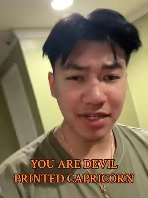 A close-up shot of a young man's face, with a warm, neutral background. The man has dark hair and is looking towards the camera with a slight smile. Overlay text in a bold, orange font reads, 'YOU ARE DEVIL PRINTED CAPRICORN'.