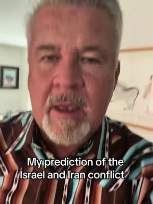 A man with gray hair and a trimmed beard is centered in the frame, set against an indoor backdrop. He wears a patterned shirt with hues of brown, blue, and orange. Text overlaid on the bottom of the image reads, 'My prediction of the Israel and Iran conflict'. The background subtly features a framed picture and wall art.