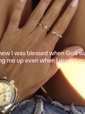 Close-up view of a woman's hand adorned with rings and a wristwatch. The image is softly lit with warm tones, focusing on the hand and a portion of the denim clothing. The text overlay is pastel, with a hint of a flesh-toned background.