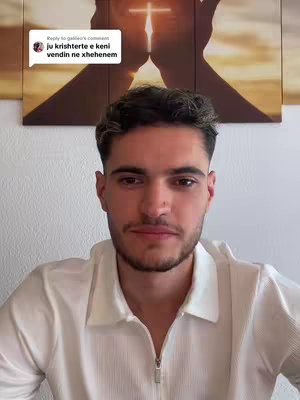 A man with short brown hair and a white shirt with dark hair is centered and looking directly at the camera. Above him is what appears to be an image of a cross in a gold and white background.
