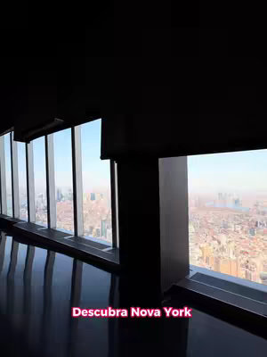 The cover image shows a view from inside a high-rise building, looking out through large windows. The scene captures a panoramic view of a city skyline under a clear blue sky. The interior of the building has dark walls, floor and ceiling. The bottom of the image has a text overlay.