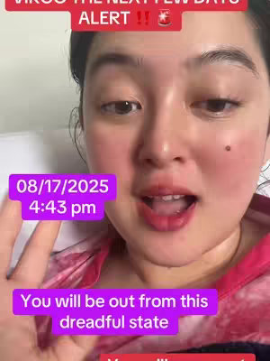 A selfie-style video cover image centered on a woman with fair skin and dark hair. She is looking at the camera with a slightly open mouth, suggesting she is speaking. Text overlays include the date and time, and overlaid text. The overall color scheme is warm, with tones of pink and purple. The woman appears to be indoors.