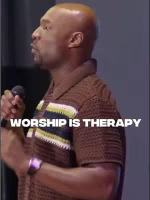 A man is shown from the side, speaking into a microphone. The image is dominated by him and text in white overlay that reads "WORSHIP IS THERAPY."