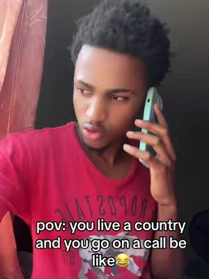 A young Black man is on a phone call, with a slightly panicked expression. Overlay text reads 'pov: you live a country and you go on a call be like 😂'. He wears a red t-shirt, and the background shows a window.