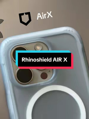 The image showcases an iPhone case in a close-up shot. The case is made of clear plastic that obscures the back of the phone. The camera lenses, flash, and charging ring are all visible through the case. A text banner with, 'Rhinoshield AIR X' is also visible.
