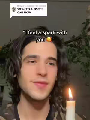 A young man with dark hair holds a lit candle in a dimly lit setting. A text overlay reads, "I feel a spark with you," with a smiling emoji. A speech bubble in the top left corner says, "WE NEED A PISCES ONE NOW."