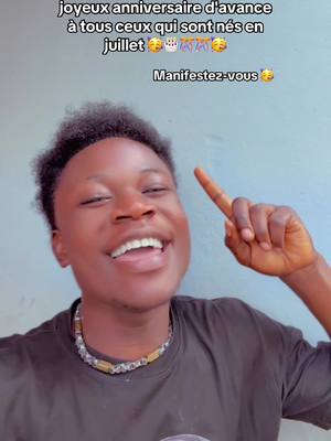 A young man with dark curly hair smiles widely, pointing his right index finger upwards. He has dark skin and is wearing a black t-shirt and a beaded necklace. Above him is text in French on a blue-gray background.