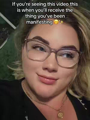 A selfie-style shot featuring a woman with fair skin and light blonde hair. She wears glasses and a black top. The background appears to be out of focus, possibly a grassy area. Text is overlaid at the top, with motivational messaging.