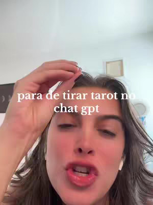 A close-up shot of a woman looking up at the camera, with a hand raised slightly as if giving a command. She has fair skin, dark hair, and is wearing small white earbuds. Text overlayed on the image read 'para de tirar tarot no chat gpt'. The background is a simple white wall with a hint of a picture frame.