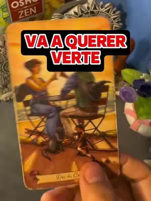 The cover image shows a tarot card held in a hand. The card depicts two figures at a table, presumably engaged in a conversation, next to a smaller dog. A black rectangle with white text overlays the card. The background is slightly out of focus, featuring other items. The overall color palette includes warm tones with touches of blue and green. The image is held by a human hand.
