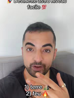 A man with short, dark hair is centered in a selfie-style shot. The man has a light complexion, a neatly trimmed beard, and is looking directly at the camera and talking. Text overlays the image, with emojis and numbers. In the backdrop, the room consists of a plain wall and a white headboard.