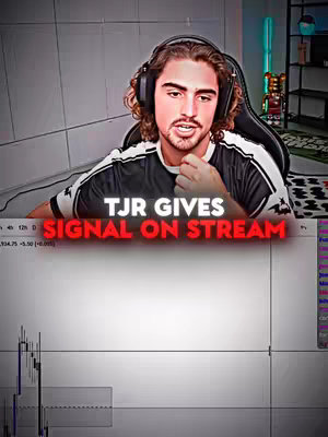 A man with long curly hair wearing headphones and a t-shirt, is in front of a computer and speaking. The video features overlaid text that reads "TJR GIVES SIGNAL ON STREAM" in a red and white font. The layout is designed around a live trading environment, including charts.