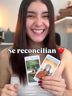 A smiling woman with long, dark hair holds two tarot cards in front of her. Text overlayed reads 'Se reconcilian' with a heart emoji. The background shows a room with soft lighting.