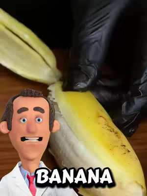 The cover image shows a close-up of a claymation figure dressed as a doctor, partially obscuring a yellow banana being peeled by a gloved hand. The banana is the focus, with the word "BANANA" in bold, white text overlaid at the bottom. The claymation figure is in the lower-left corner, with a neutral expression. The overall color palette is dominated by the yellow of the banana, contrasted with the black glove and a brown background, creating a focus on the fruit.