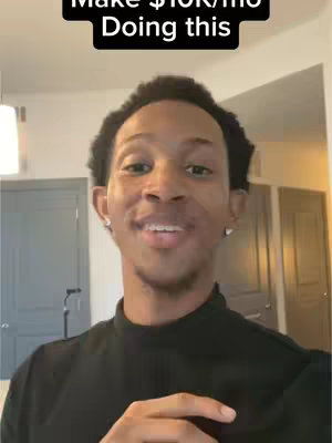 A selfie-style video cover featuring a young man speaking with a direct gaze. Above him, text overlaid in a black box reads, \"Make $10K/mo Doing this\". He's wearing a black turtleneck, with a light-colored interior visible behind him, including a closed door. The overall composition is simple, focusing on the man and the overlaid text, with a warm, inviting feel.