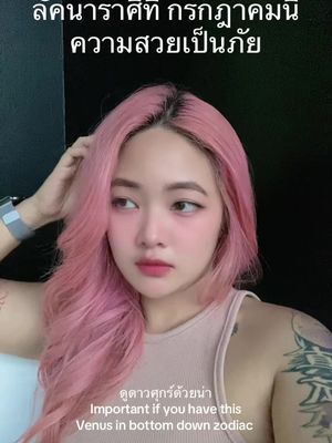 A selfie-style image featuring a young woman with pink hair and makeup. Text overlays in Thai and English are present. The background is a plain, dark wall.