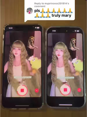 The scene presents an image of two smartphones side-by-side, showcasing a cosplay video in progress. The phones are capturing the same content, which depicts a person dressed as a character with long, wavy blonde hair and a light-colored dress. Each phone screen displays a recording interface with red circular record buttons. The background appears to be a neutral wooden surface, with a comment box overlaying one phone displaying the text: 'pls 🙏🙏🙏🙏🙏🙏 truly mary'