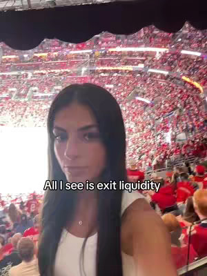 A young woman with long dark hair stands facing the camera in a large arena filled with spectators. The arena is lit with bright red and white lights, while the woman is wearing a white top, and the hook text is overlayed.