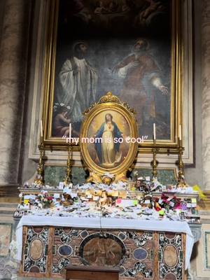 An image of a religious altar or shrine with an ornate painting of religious figures and an oval framed portrait of Jesus Christ. In the foreground, a table is displayed with papers and flowers. The added texts overlay reads "my mom is so cool."