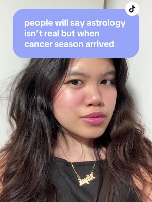 A selfie-style shot features a young woman with dark hair and fair skin. She is centered in the frame, and a text overlay is positioned above her head. The woman has a neutral expression with slightly parted lips, and a necklace with the name 'Kaylee', inscribed in cursive. The background is a plain, off-white wall. The image uses minimal makeup, with a focus on natural features, creating a casual, friendly tone.