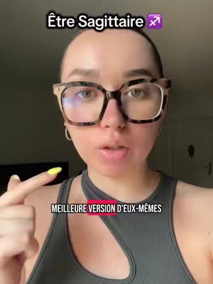 A woman with fair skin and a buzz cut is the central figure, wearing large, thick-rimmed glasses. She's facing the camera directly, with a neutral expression and her mouth slightly open. Text overlays in bold white letters. Her top is a dark gray, sleeveless garment cut with a unique asymmetrical design. The background appears to be an interior wall, with muted tones.