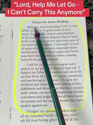 A photo featuring a page from an open book. Text is visible, partially highlighted with a yellow marker. A pen is pointing to the text, which appears to be a prayer written in English.