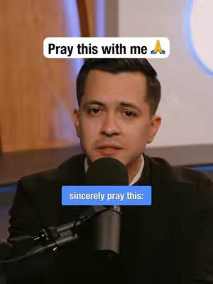 A man with short, dark hair, wearing a black blazer, is centered in the frame. He is positioned slightly off-center, gazing towards the lower center. A black microphone is placed directly in front of the mouth. A white rectangular text box with curved corners appears near the top of the image, with the text 'Pray this with me' in a black font. A blue rectangular text box reading 'sincerely pray this:' is present below the microphone.
