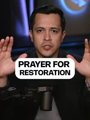 A man with a medium complexion is centered in front of the camera. The background is blurred and dark. He is wearing a black shirt. His hands are up near his face with his palms facing out. White text on a white background reads "PRAYER FOR RESTORATION".