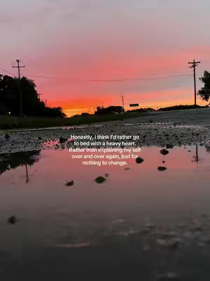 A photograph of a sunset reflected in a puddle of water. The sky is a gradient of orange and pink hues. The water reflects the sky, with the addition of darkened areas. Reflections of trees and utility poles are visible to the sides, and text overlaid on the image provides context.