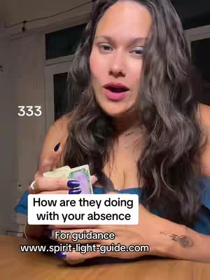 A medium-shot selfie-style video featuring a woman holding a deck of cards, presumably tarot cards, in front of her chest. The color scheme is natural, the environment appears to be indoors. The woman has long dark hair, and makes eye contact with the camera directly.
