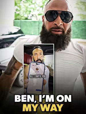 A muscular, bald man with a large black beard and sunglasses is the central figure. He's wearing a white t-shirt, and the background appears to be outdoors, possibly near a vehicle. In the image's center, there is a framed image of a man holding a phone with a social media interface. Below the main figure are the words "BEN, I'M ON MY WAY" in bold, white letters.