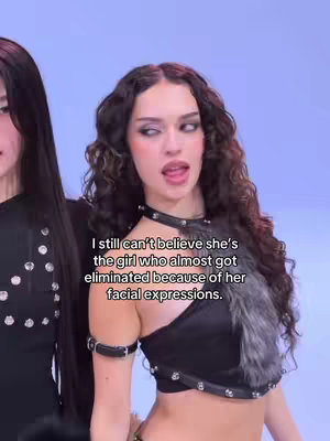 The image shows a woman with long, dark, wavy hair looking slightly to the side with her mouth partially open. She has a pale complexion, dark eye makeup, and wears a black top and choker with studs. A second woman is partially visible on the left, and text is overlaid, describing a past event.