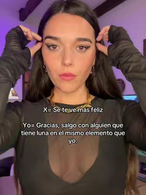 A front-facing shot of a woman with dark hair, wearing a black top and holding her hands near her temples. Text overlays are present, and the background seems to be a room with some soft lighting.