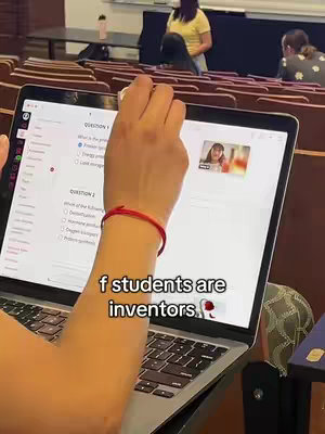 The cover image shows a laptop displaying a quiz question; a person's hand is partially visible, pointing at the screen. In the corner, a small video displays a smiling face, with a person in the background. The text overlay displays the caption 'f students are inventors.' The setting appears to be a classroom.
