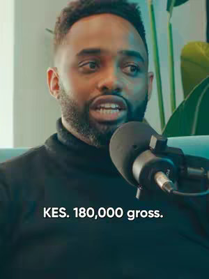 The cover image is a medium shot featuring a Black man with short, neatly styled hair, a beard, and wearing a black turtleneck. He's positioned slightly off-center, looking to the side with an engaged expression, his mouth open as if speaking. A microphone is close to his mouth, suggesting a recording or interview setting. The background is softly blurred, with hints of a light-colored wall and green foliage to the right. Overlayed at the bottom of the frame, white text reads 'KES. 180,000 gross.'