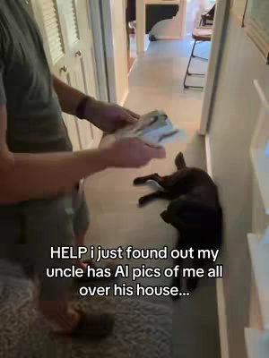 A man is holding a stack of papers in his hands, standing in a doorway. A black dog is laying down on the floor nearby. The room has white walls, a wooden floor and is quite bright with natural light.