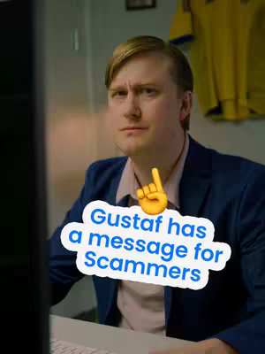 A man with blonde hair sits at a desk, looking towards the viewer in front of a computer screen, with a humorous text overlay placed on the image. Behind him, a yellow sports jersey hangs on the wall.