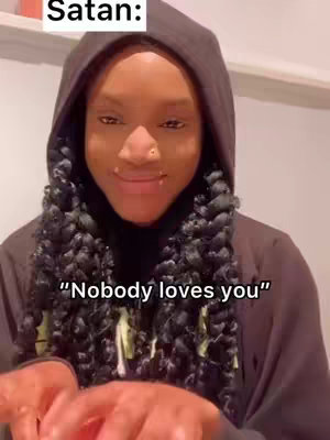 A close-up of a young woman with long, braided hair and a black hoodie. Text overlays are placed at the top and bottom, while she maintains a thoughtful expression.